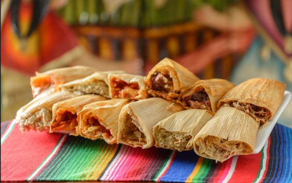 tamales with various fillings stacked on Mexican blanket