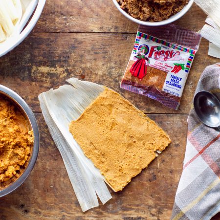 Seasoned tamale masa spread on a corn shuck