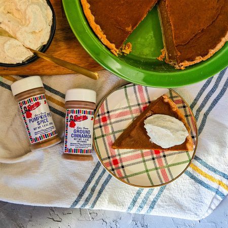 Pumpkin Pie with slice on plate and large dollop of whipped cream on top