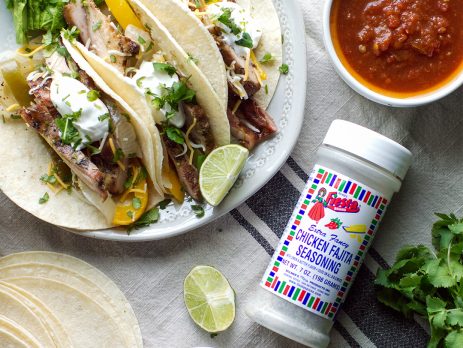 Chicken fajita tacos with grilled peppers, lime wedges, and sour cream served with salsa